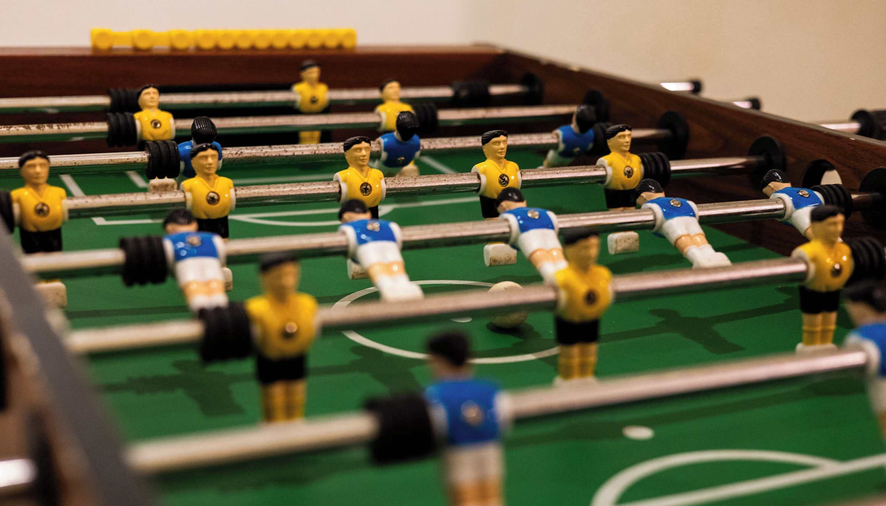 A foosball table with players in yellow and blue uniforms.