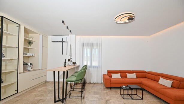 A modern living room with a sectional sofa, a dining area with chairs, and a kitchen with cabinets and a refrigerator. - Villa Donatus Zadarvillas (Policnik)