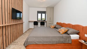 A modern bedroom with a large bed, a TV mounted on a wooden wall, a desk with two chairs, and a wardrobe. - Villa Donatus Zadarvillas (Policnik)