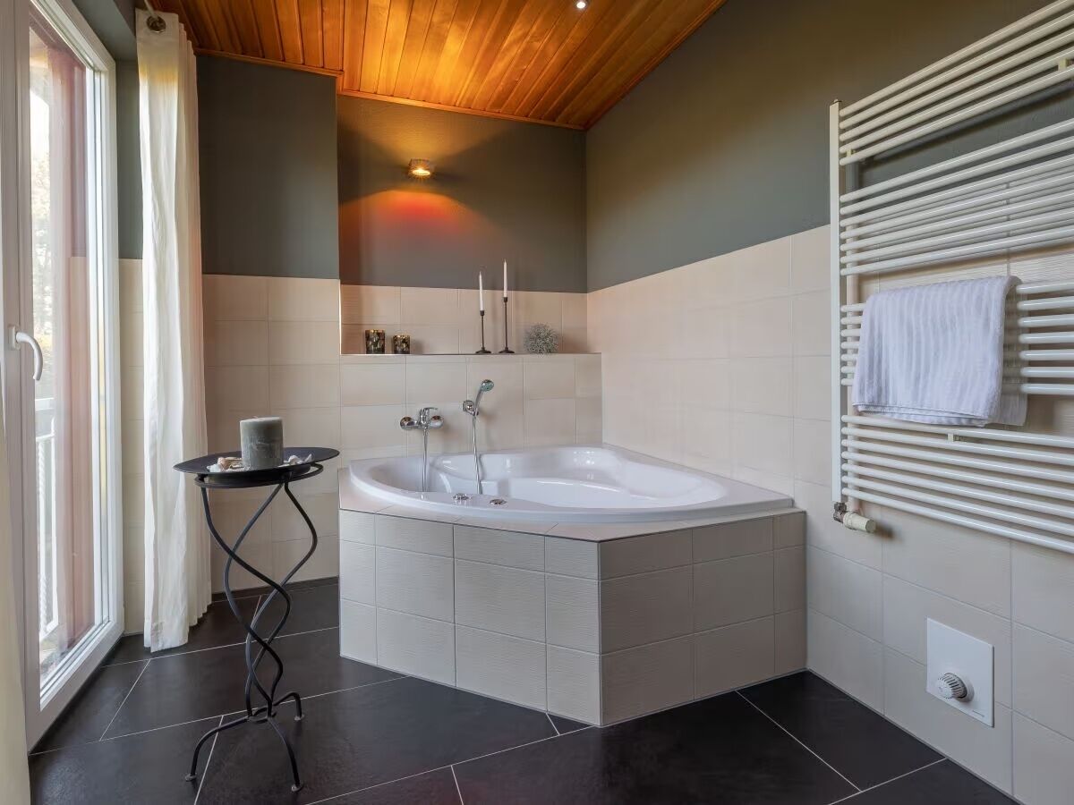A modern bathroom with a freestanding bathtub, a small table with a candle, and a towel rack.