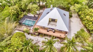 Ein Haus mit einem Satteldach, einem Pool und dichter tropischer Vegetation.