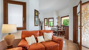 Ein Wohnzimmer mit einem braunen Ledersofa, einem Tisch mit einer Lampe und einem Essbereich mit Stühlen und einem Tisch.