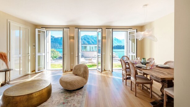Una habitación amplia con una mesa de comedor de madera, sillas, un sofá y un gran ventanal con vistas a la montaña.