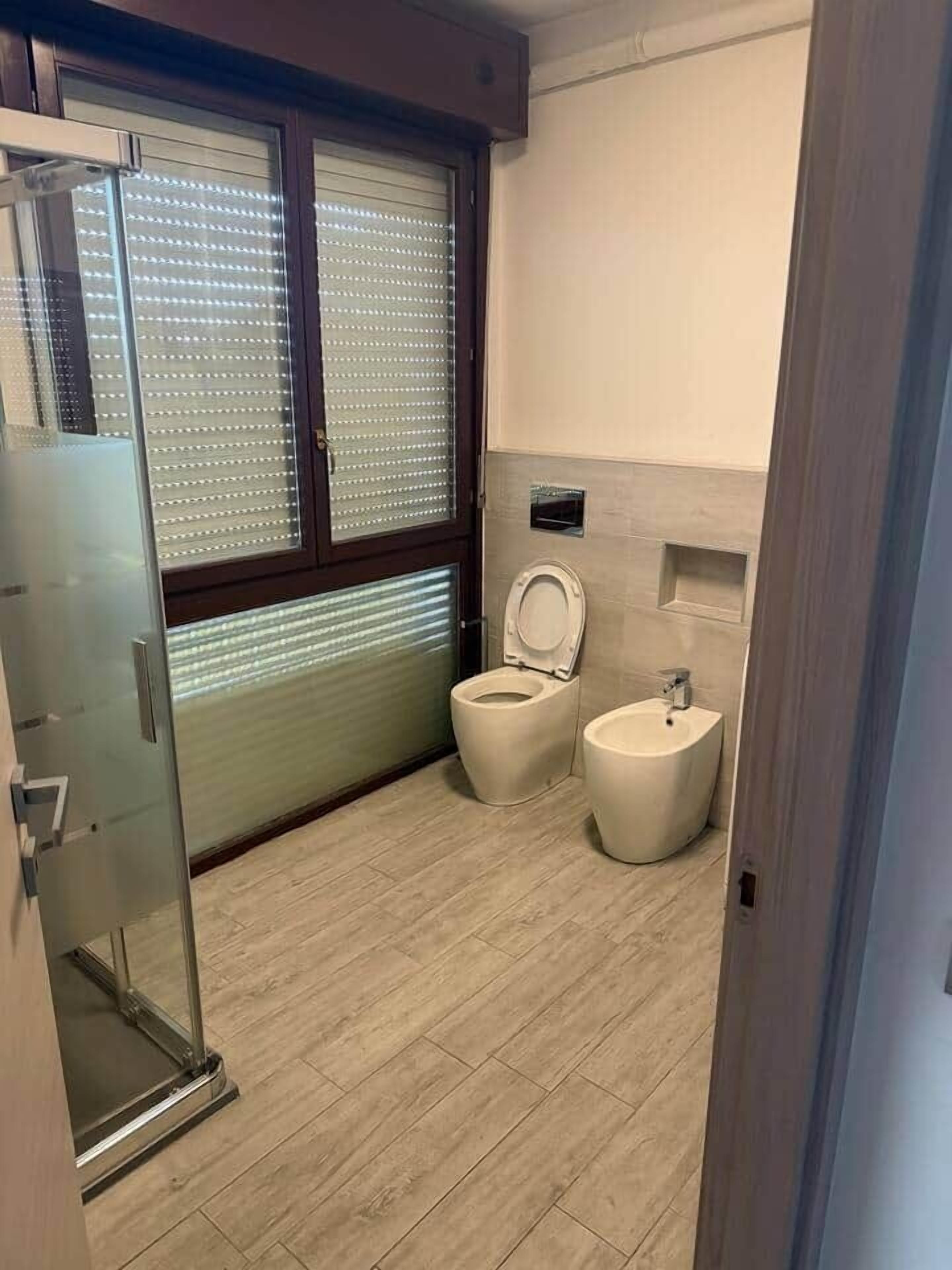 Ein modernes Badezimmer mit Toilette, Bidet und einer Duschkabine aus Glas.