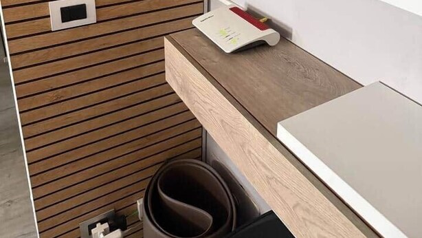 Ein modernes Badezimmer mit einer Wand aus Holzlamellen, einem weißen Waschbecken und einem Spiegel.