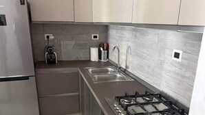 Eine moderne Küche mit Edelstahlkühlschrank, einer doppelten Spüle, einem Gasherd und einem eingebauten Backofen.
