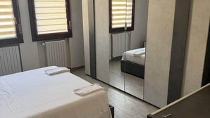 Ein Schlafzimmer mit Bett, Kleiderschrank, Spiegel und Heizkörper.