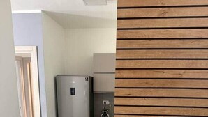 Eine moderne Küche mit einem Edelstahl-Kühlschrank, grauen Schränken und einem Fischgrätparkettboden.
