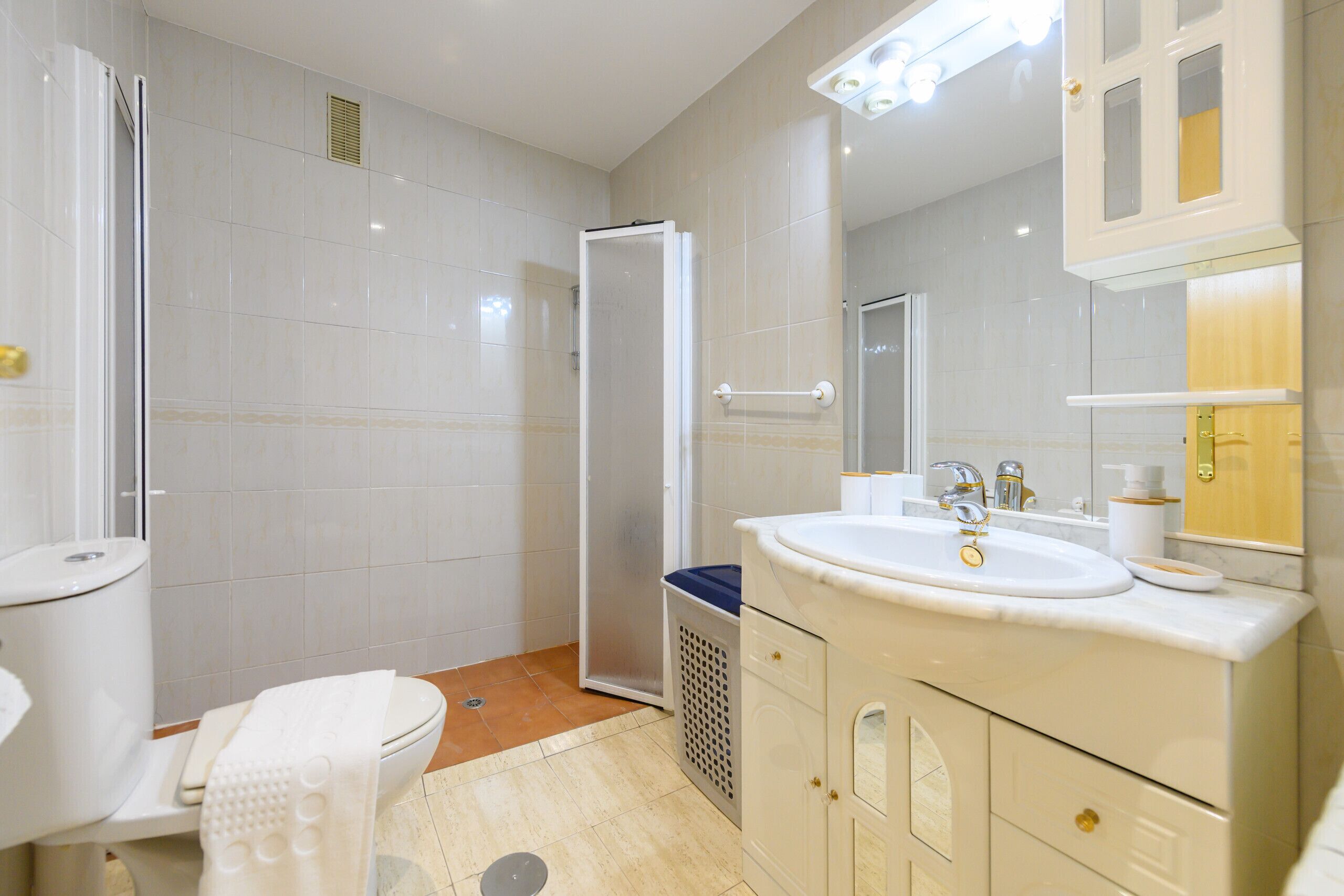 Une salle de bain comprenant des toilettes, un lavabo, un miroir et un espace douche.
