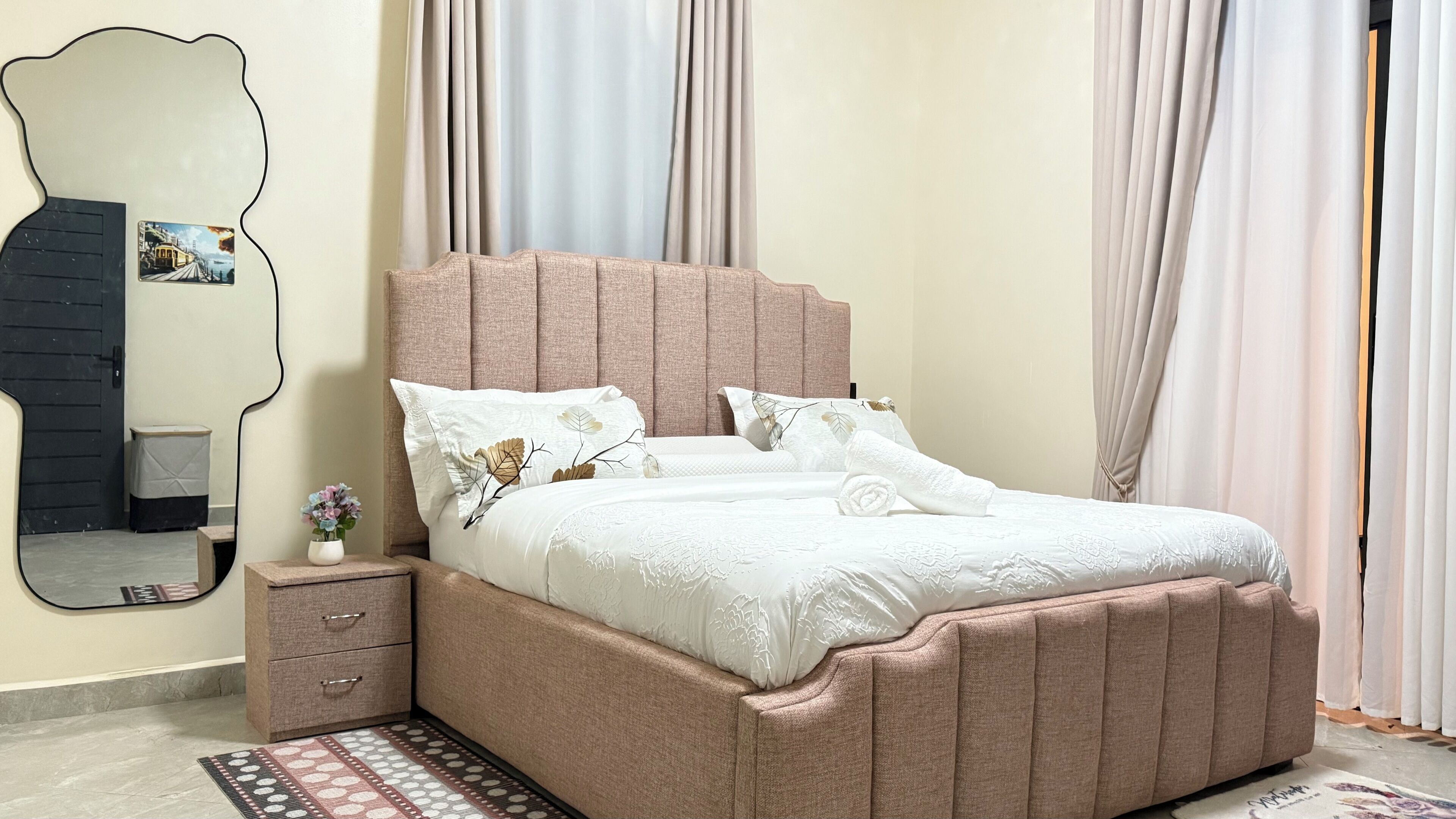Una camera da letto con un letto, un comodino, uno specchio e tende.