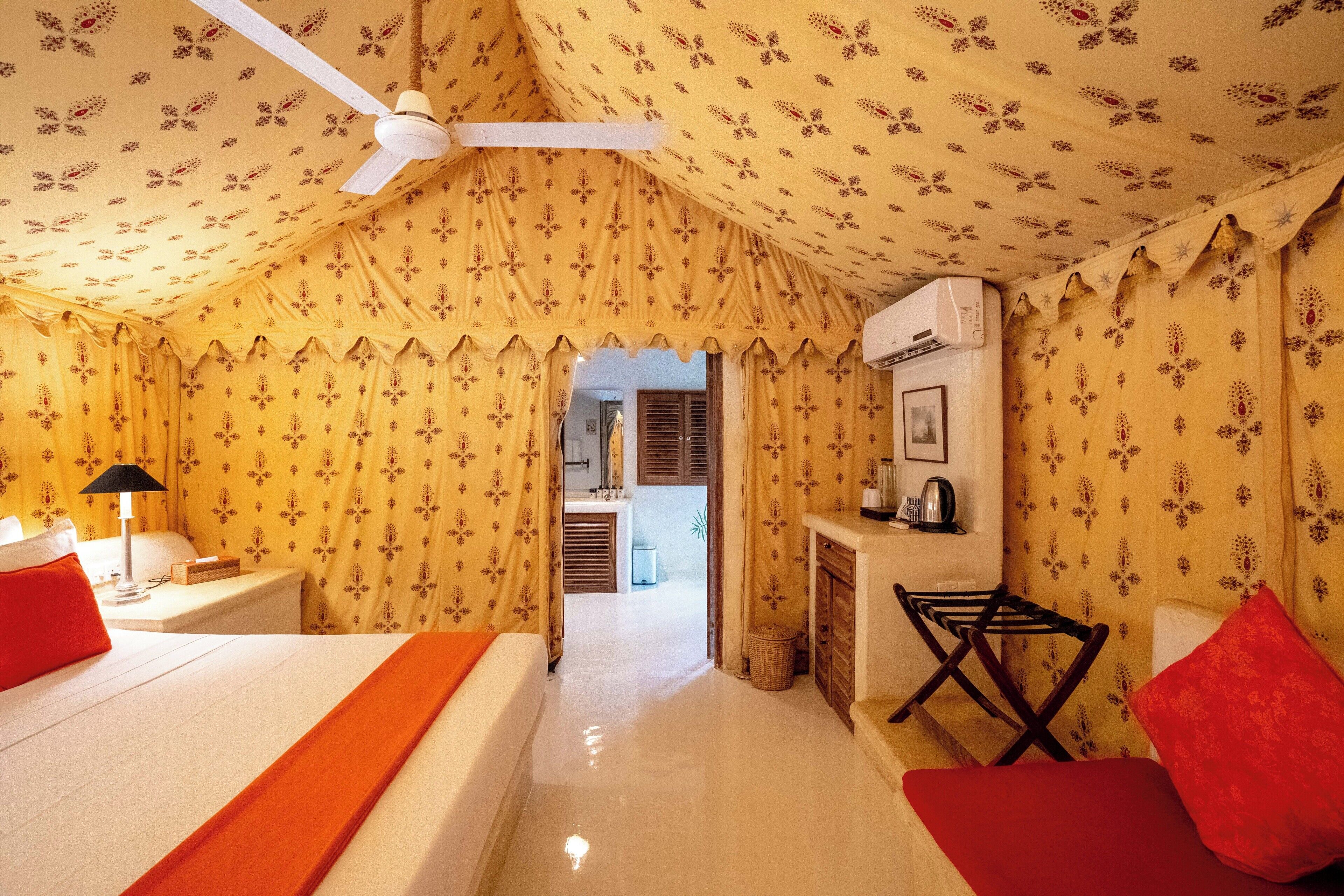 A room with a bed, a nightstand, a lamp, a chair, and a ceiling fan.