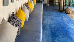 A long, narrow seating area with a blue floor and cushions in various colors. - Dolphin Beach Resort (Etalai)