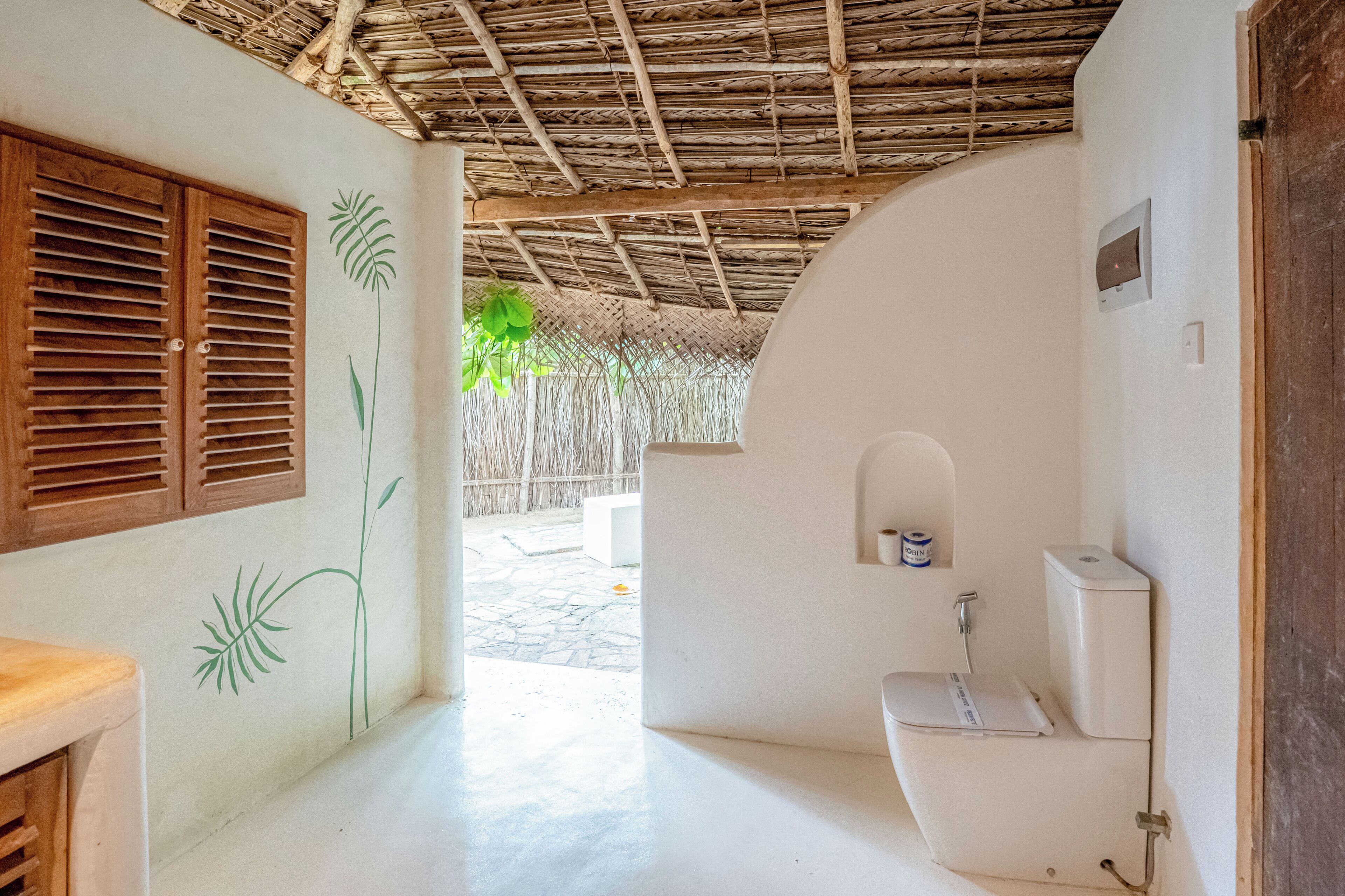 A bathroom with a white toilet, a small shelf, and a shower area.