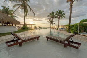 A poolside area with lounge chairs and palm trees. - Dolphin Beach Resort (Etalai)