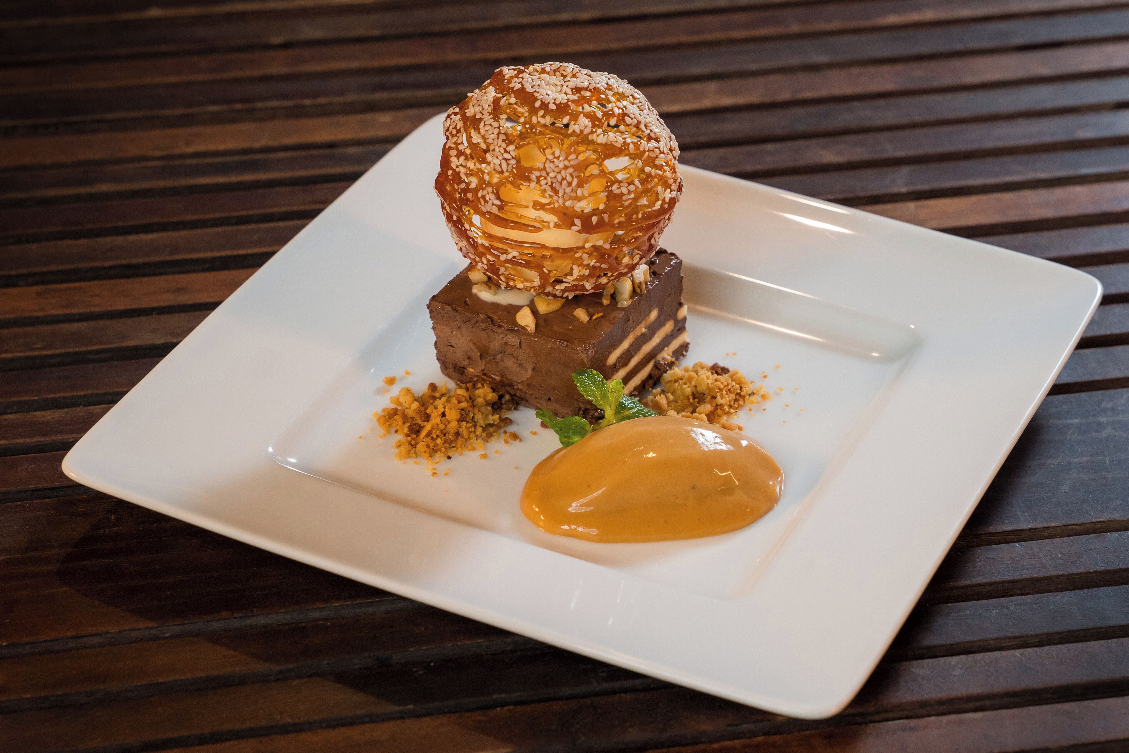 A dessert on a white square plate with a dark wooden table background.