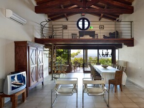 A spacious dining area with a view of the outdoors, a wooden ceiling, and a large window. - Exclusive Villa with Pool and Sea View in Is Molas – Villa Le Poiane (S. Margh. di Pula)