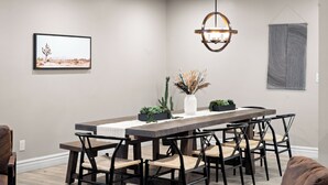 A dining area with a long wooden table, six chairs, a vase with dried plants, and a framed picture on the wall. - Sleeps 16! Luxury Phoenix Retreat Near Biltmore- Pool, Theater & Game Room. (Phoenix)