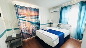 Une chambre d’hôtel avec un lit, une table de chevet, une lampe et une fenêtre avec des rideaux.
