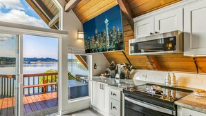 Une cuisine moderne dotée d’une grande fenêtre, offrant une vue sur les gratte-ciel de la ville, et d’une terrasse avec une rambarde en bois.