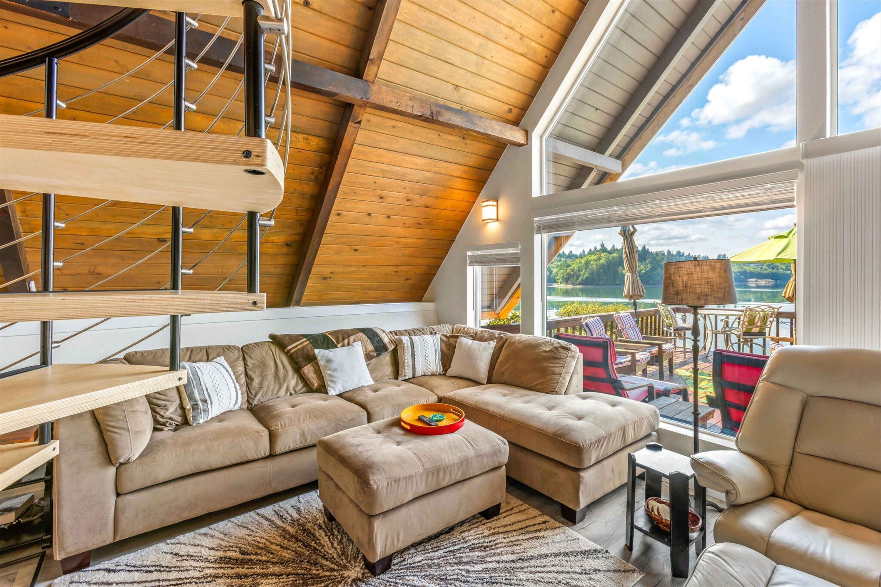 Ein geräumiges Loft mit einem großen Ecksofa, einem Holztisch und Seeblick.