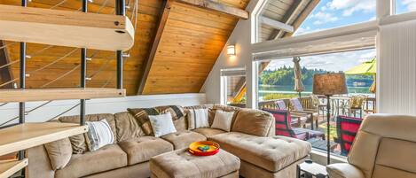 Ein geräumiges Loft mit einem großen Ecksofa, einem Holztisch und Seeblick.