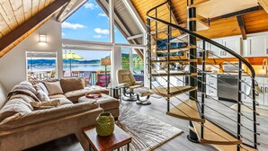 Un loft spacieux doté d’un grand espace de vie, d’un escalier en bois et offrant une vue sur l’extérieur.