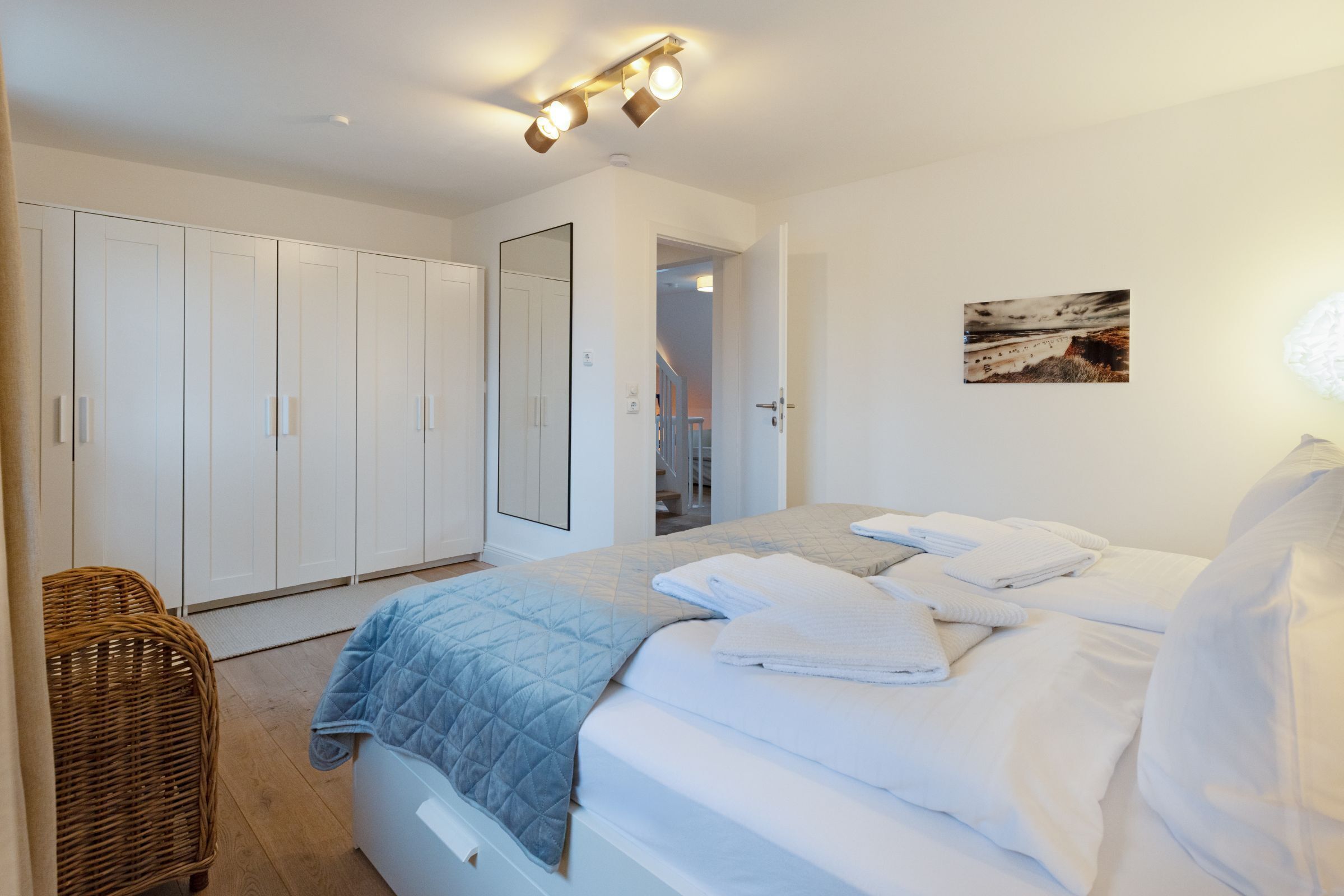 Een slaapkamer met een bed, een witte inbouwkast en een spiegel.