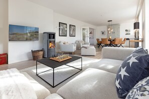 Un salon moderne avec une cheminée, un coin repas et une cuisine en arrière-plan.