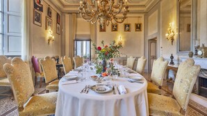 Une salle à manger élégante, avec une table ronde dressée pour le repas, entourée de chaises rembourrées.