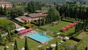 Vue aérienne d’un complexe hôtelier doté d’une piscine, de chaises longues et d’un jardin bien entretenu.