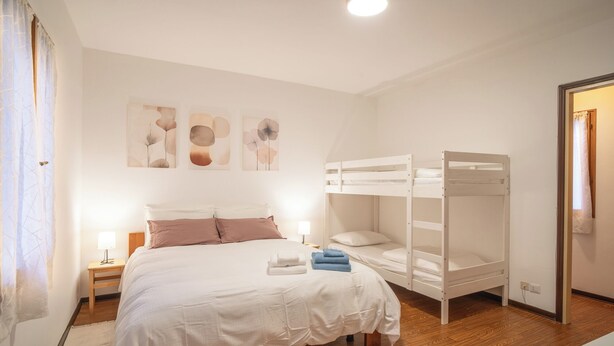 A bedroom with a bunk bed, a single bed, and a bedside table with a lamp. - La Casetta di Roveredo, independent house. Near the Dolomites and Aviano Base (Roveredo in Piano)