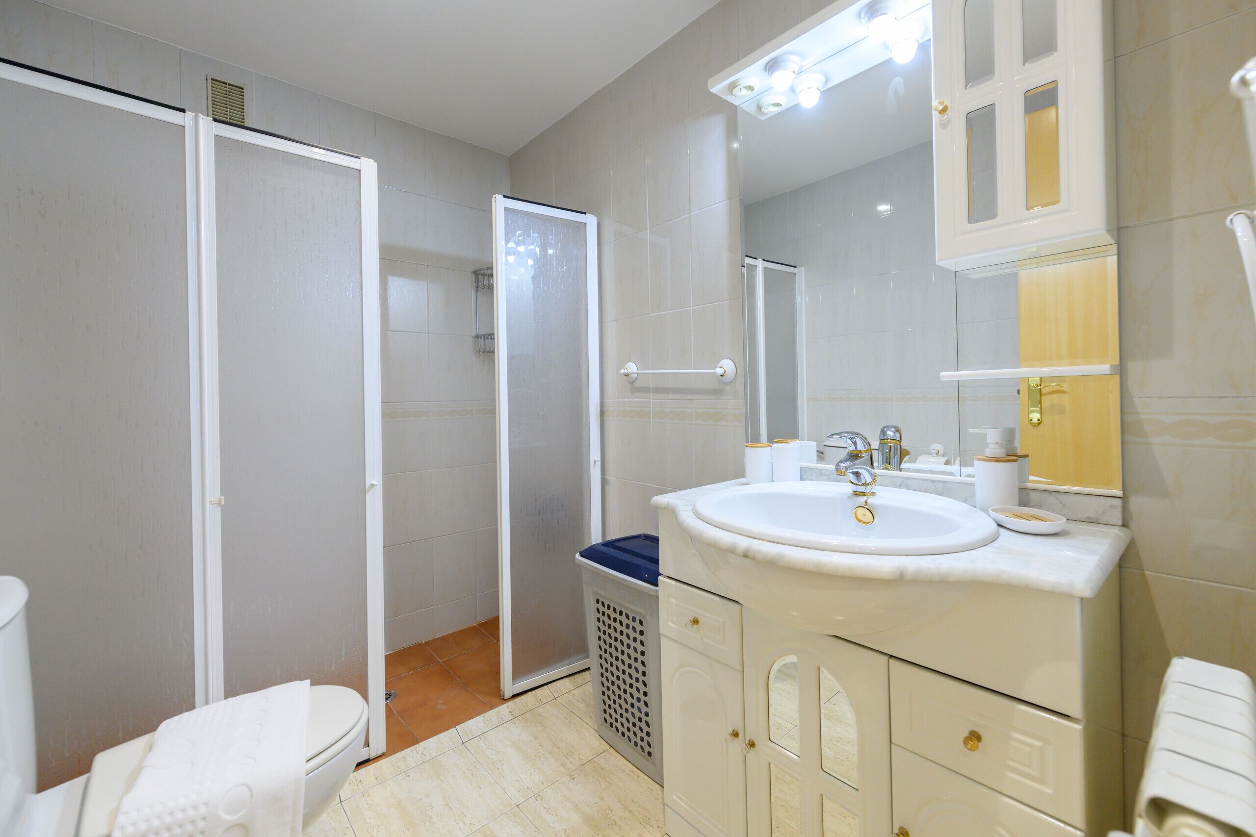 A bathroom with a toilet, a sink with a mirror, and a shower stall.