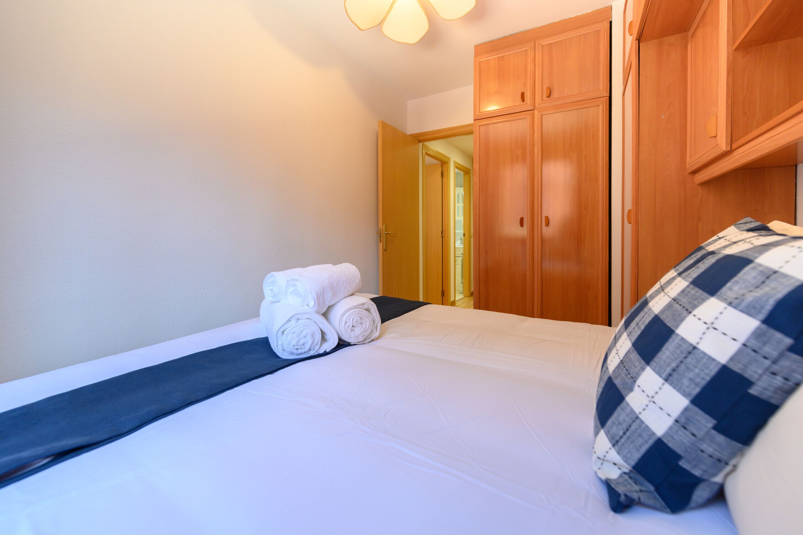 Une chambre d’hôtel avec un lit, un ensemble d’armoires en bois et une porte donnant sur une autre pièce.