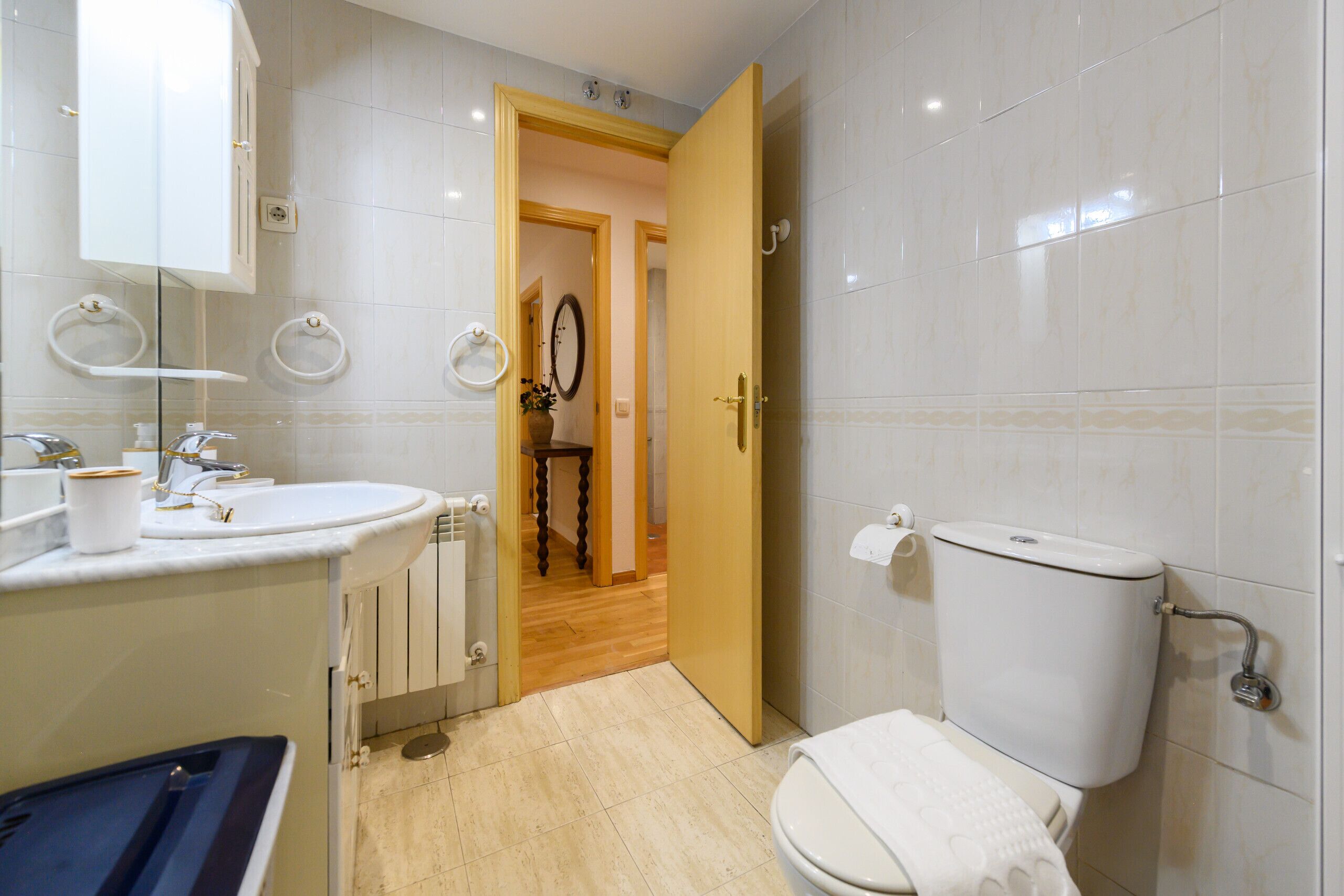 A modern bathroom with a white sink, mirror, and toilet.