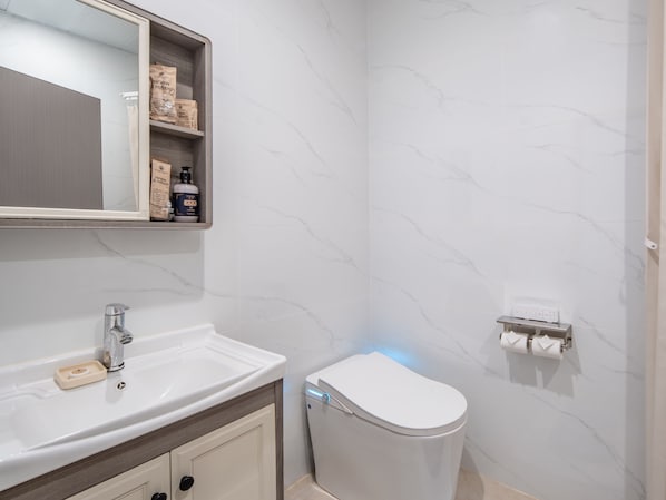 A bathroom with a white sink, mirror, and toilet. - Palau Mangrove Hotel (Meyungs)