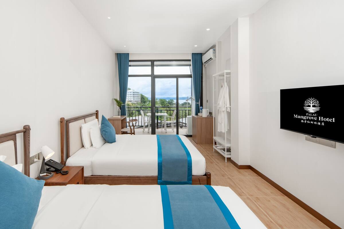 Ein Hotelzimmer mit Bett, Nachttisch, Fernseher und einem Balkon mit Blick.