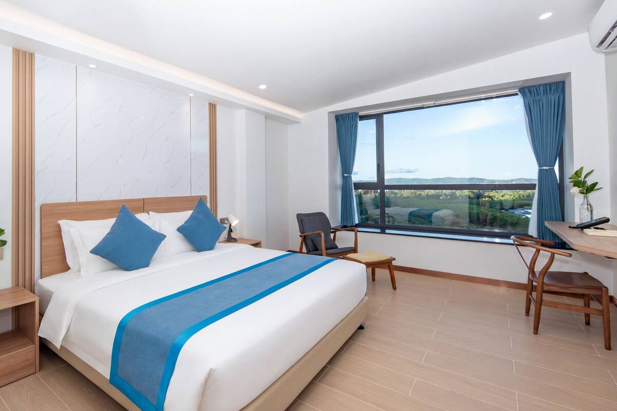 Ein modernes Hotelzimmer mit einem großen Bett, einem Schreibtisch und Blick auf eine Landschaft.