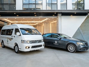 A white van and a gray car parked in front of a building with a modern design. - Palau Mangrove Hotel (Meyungs)