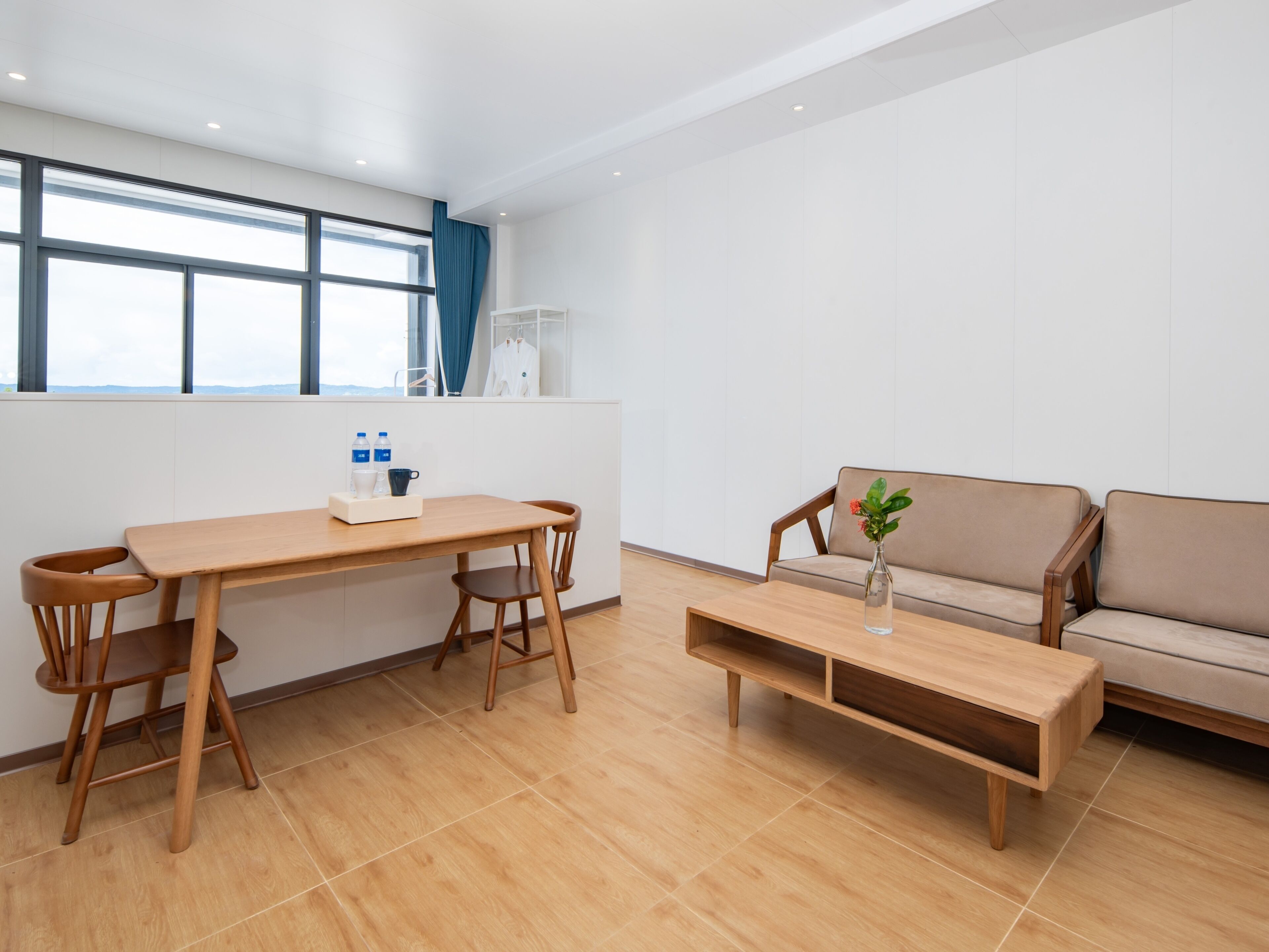 Quarto moderno com mesa de jantar de madeira, cadeiras, sofá e uma pequena mesa de centro.
