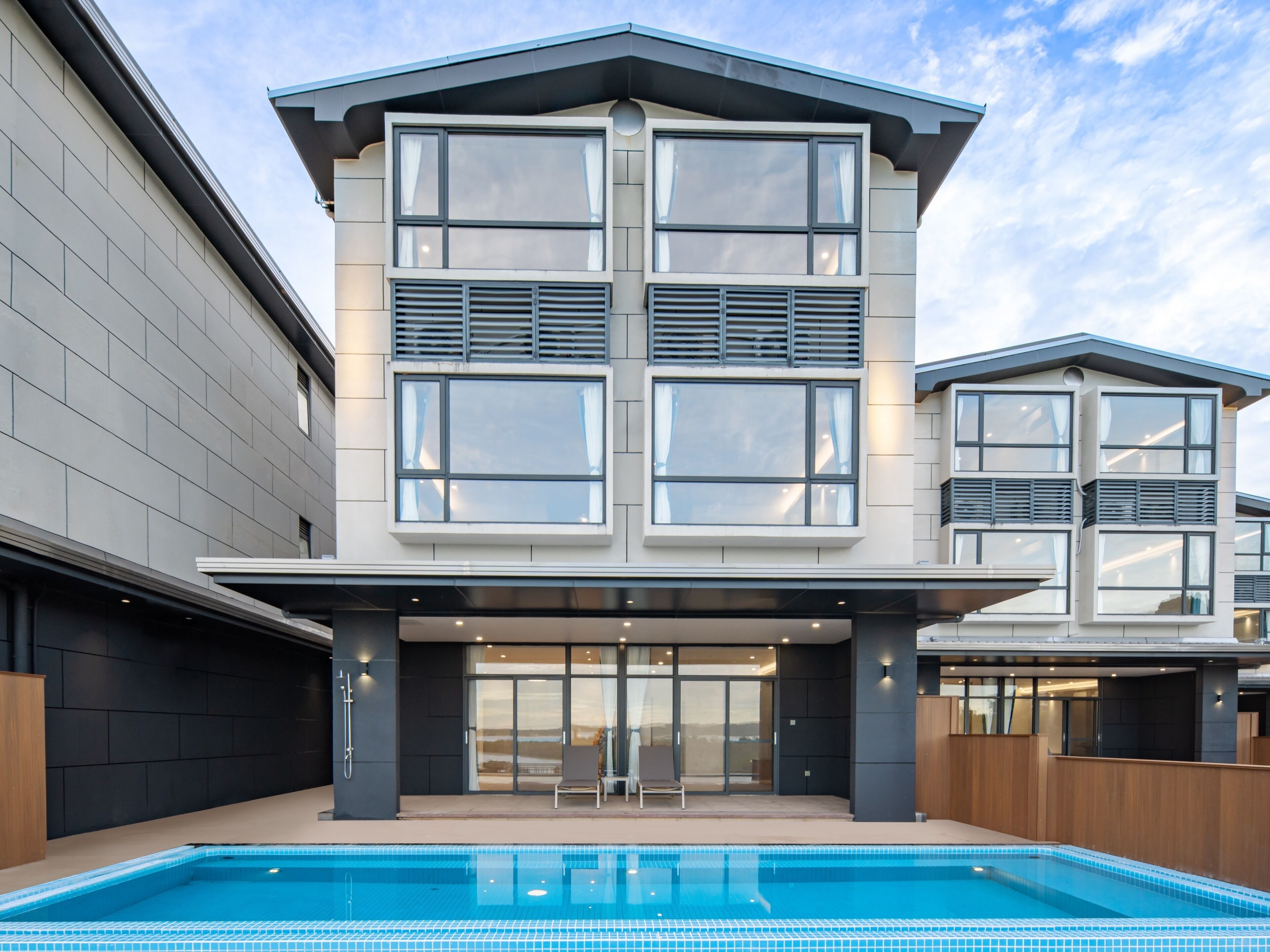 A modern building with a pool, large windows, and a flat roof.