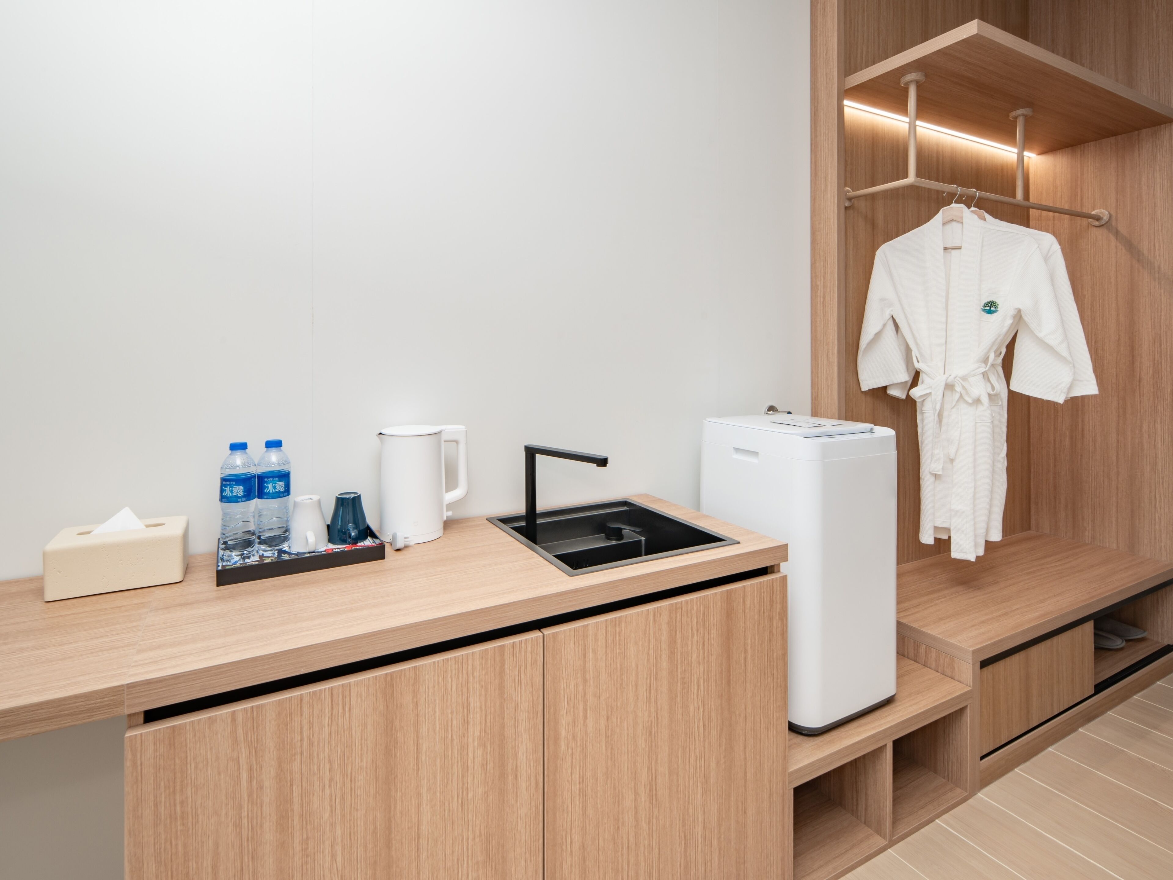 A modern bathroom with a wooden vanity, a sink, a mirror, a towel rack with a robe, and toiletries.