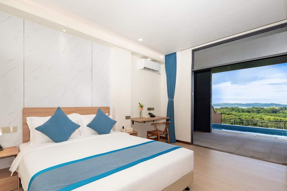 Ein modernes Hotelzimmer mit einem großen Bett, einem Schreibtisch und Blick auf eine grüne Landschaft.