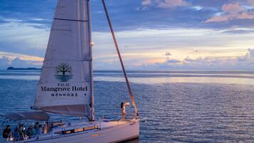 A sailboat with 'Palu Mangrove Hotel' written on its sail, docked at a marina.