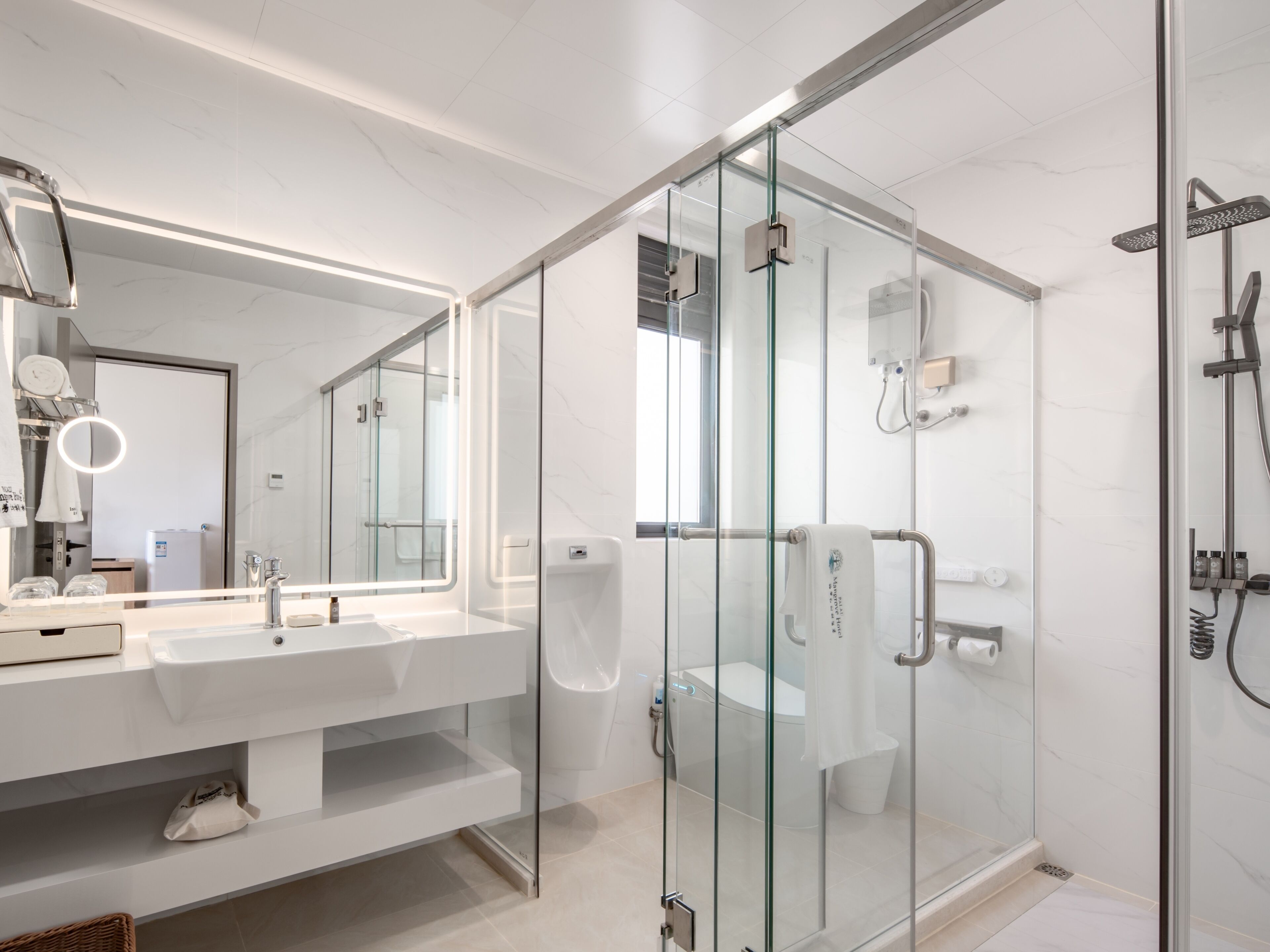 Un baño moderno con ducha de vidrio, un espejo grande y un lavamanos blanco.