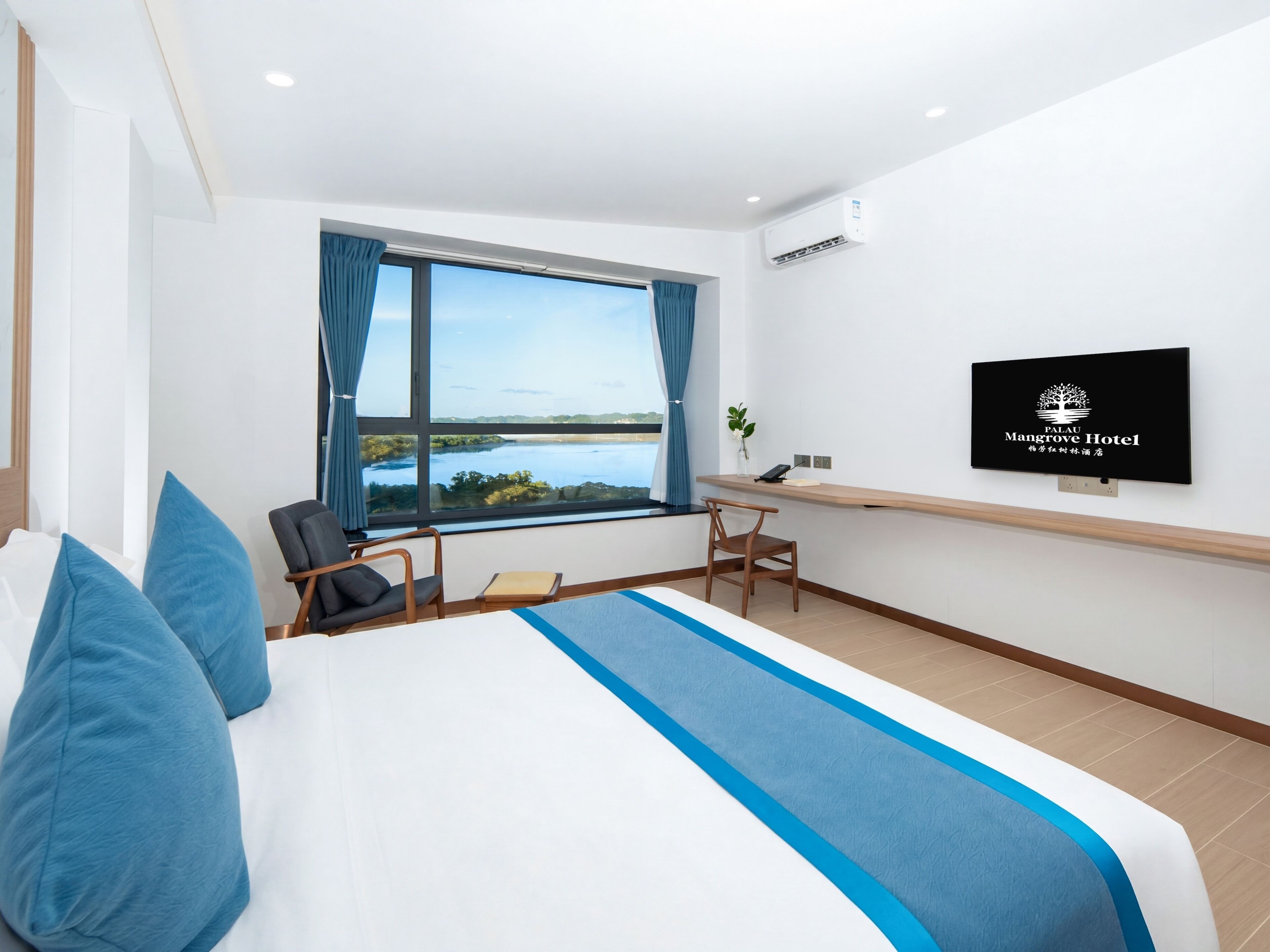 A hotel room with a large bed, a desk, a chair, a TV, and a window with a view of a body of water.