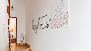 Una escalera que lleva a una habitación con una obra de arte colgada en la pared y una placa con un nombre.