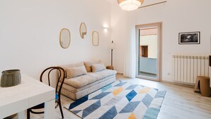 Una sala de estar moderna con un sofá, un tapete geométrico y una lámpara colgante.