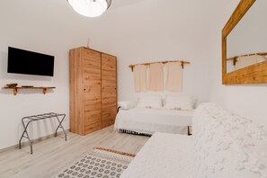 Ein Schlafzimmer mit Bett, Holzschrank, Fernseher und Spiegel.