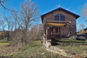 A stone building with a porch, a window, and a door. - Casa Rural Ucedo: Peace and Nature with Mountain Views (Ucedo)