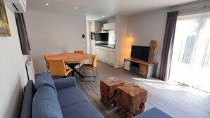 Una sala de estar moderna con un sofá, una mesa de centro de madera y un comedor con mesa y sillas.